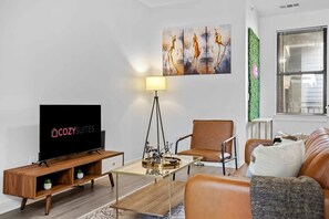 Relax in this stylish living room with a flat-screen TV, comfortable sofa, and a beautiful abstract art piece.
