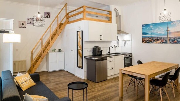 Eine kompakte Wohnung mit Küchenzeile, Essbereich und Wohnzimmer mit Sofa und kleinem Tisch.