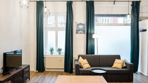 Ein modernes Wohnzimmer mit einer Couch, einem Fernseher und einem Esstisch.