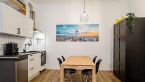 Eine moderne Küche mit weißen Schränken, einem Holztisch und einem Stadtbild an der Wand.