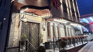 A building with a stone facade, multiple flags, and outdoor seating. - Aleppo Hotel in Yerevan (Yerevan)