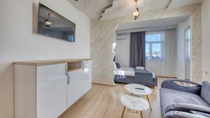 A modern living room with a sofa, a coffee table, and a TV mounted on the wall. - Aleppo Hotel in Yerevan (Yerevan)