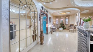 A spacious lobby with a large arched window, a Christmas tree, and a reception desk. - Aleppo Hotel in Yerevan (Yerevan)