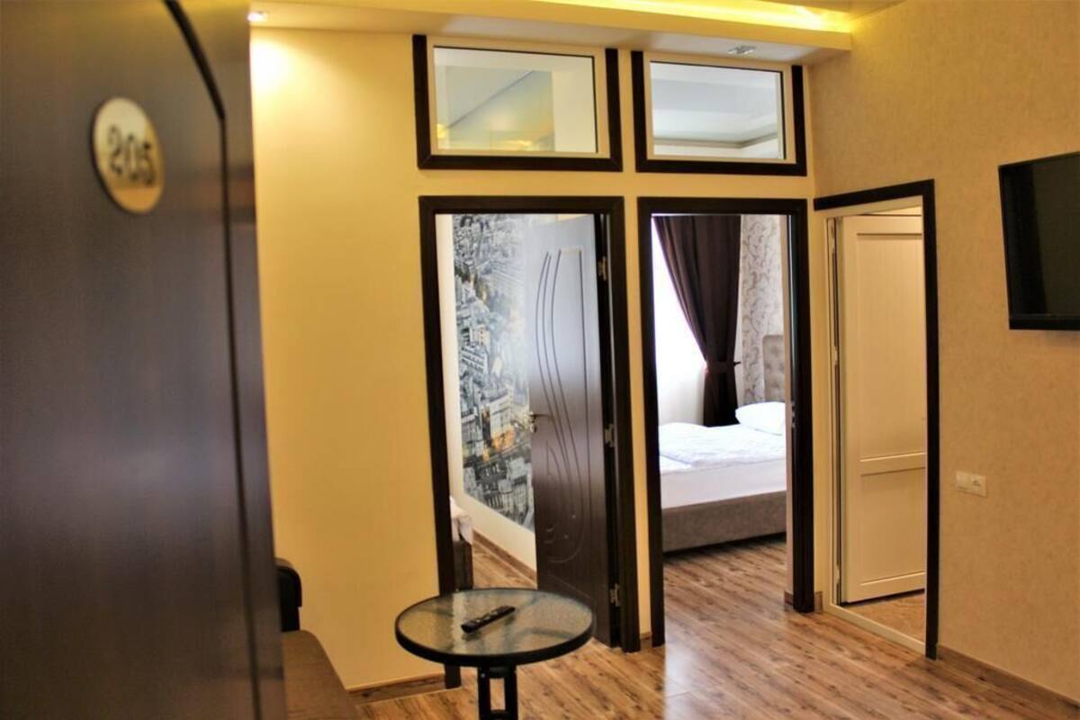 A hotel room with a bed, a small table, and a TV mounted on the wall.