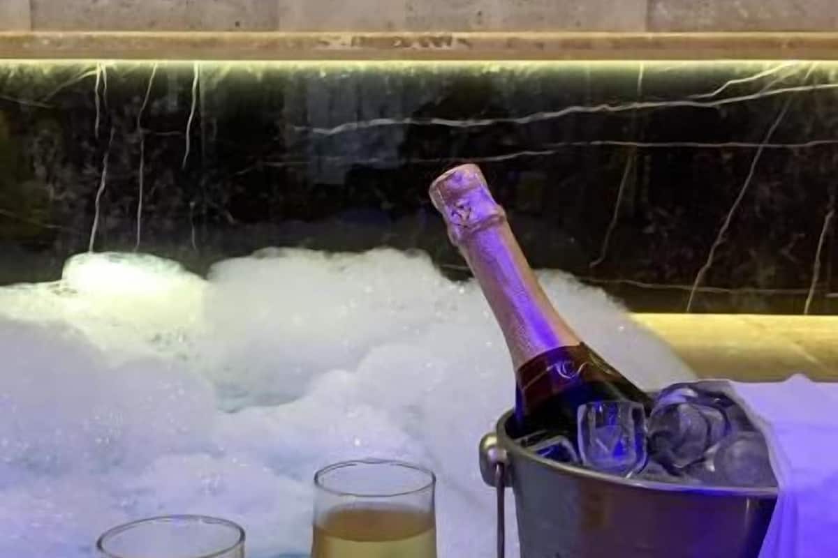 A champagne bottle in a bucket with two glasses of champagne on a table.