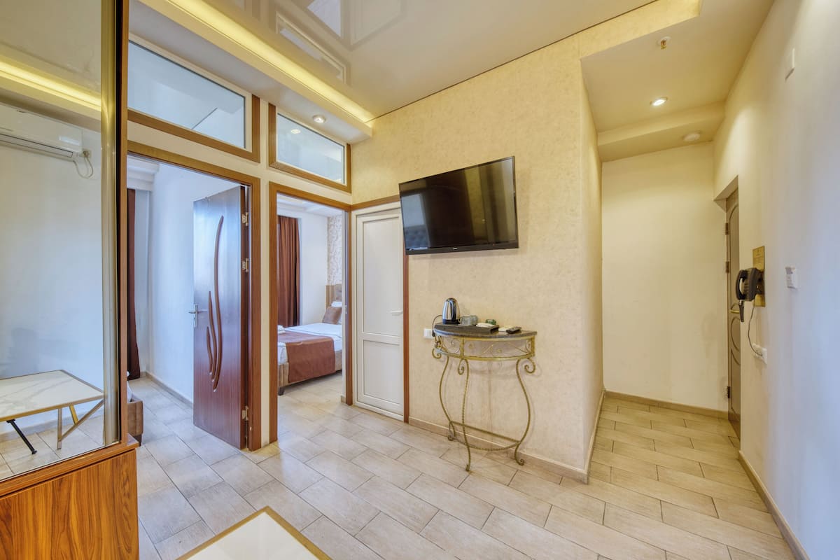 A hotel room with a large bed, a TV mounted on the wall, and a small table with a kettle.