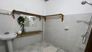 Bany amb rentaplat, mirall, dutxa i una estant amb un vas.