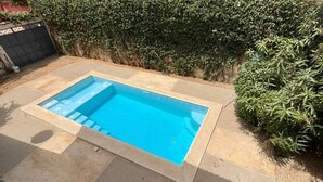 Una piscina rectangular amb aigua blava cristal·lina, envoltada per un sòl de formigó i vistes a un dens bosc verd.