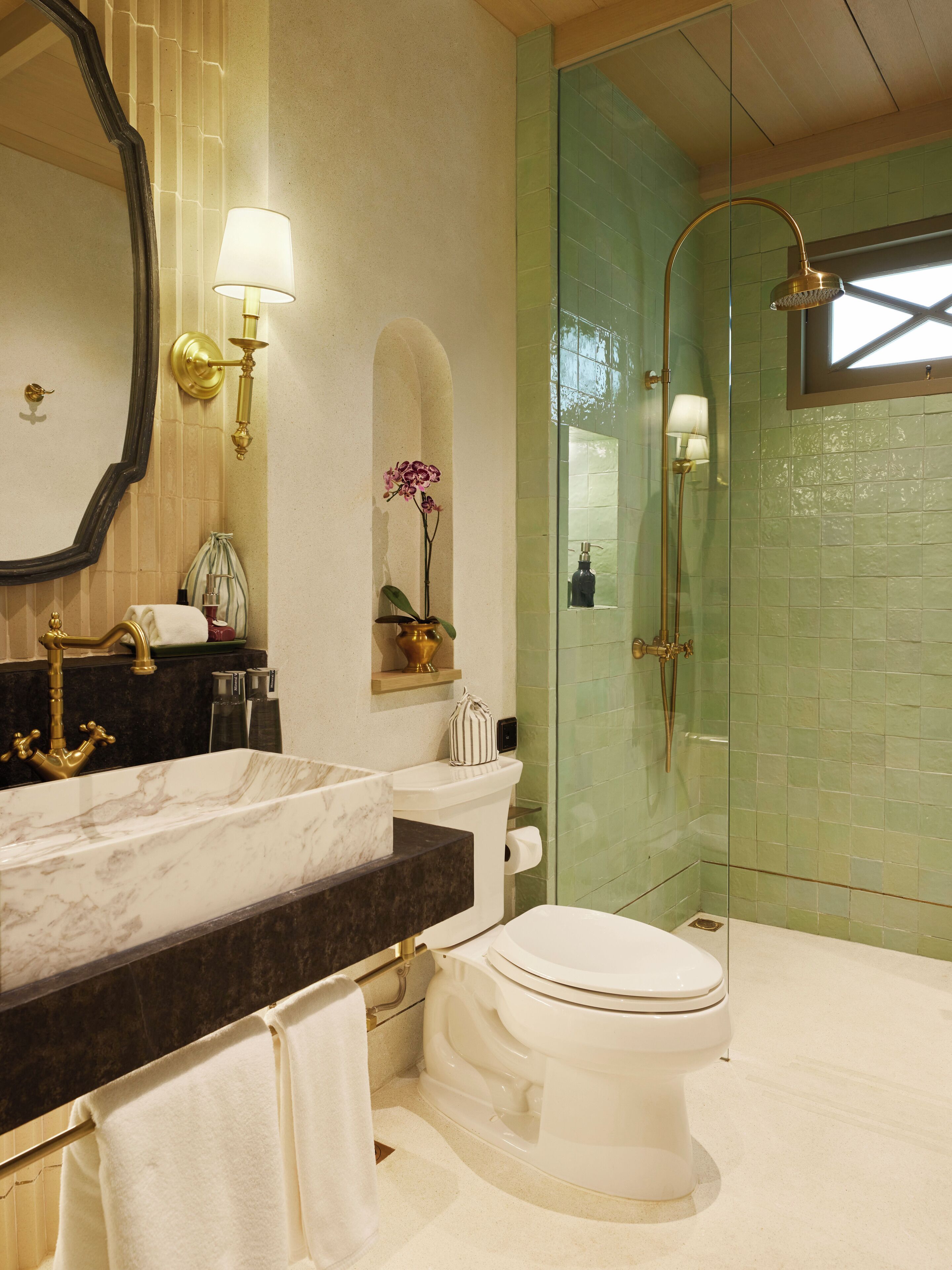 A bathroom with a marble sink, white toilet, and a glass-enclosed shower.