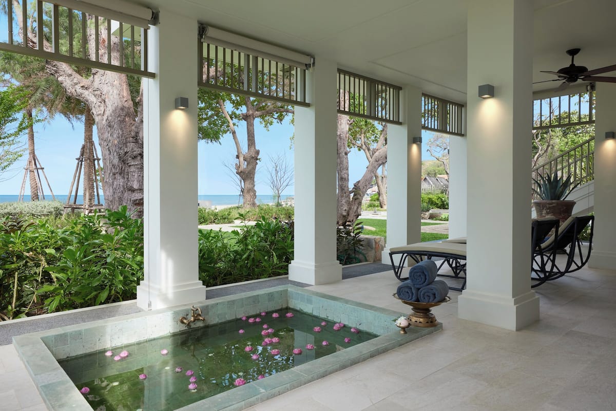 Ein überdachter Außenbereich mit Pool, Sitzgelegenheiten und Meerblick.