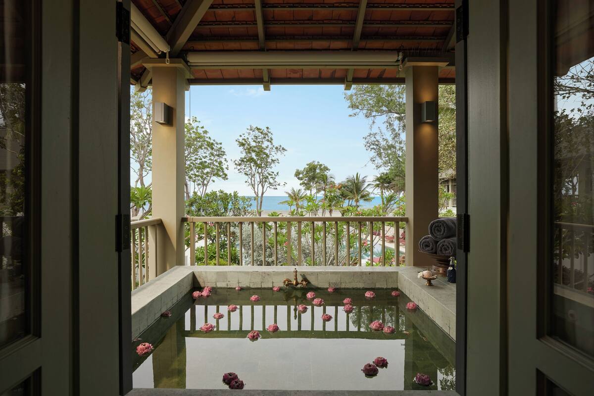 Blick vom Balkon auf eine Wasseranlage, Palmen und einen klaren Himmel.