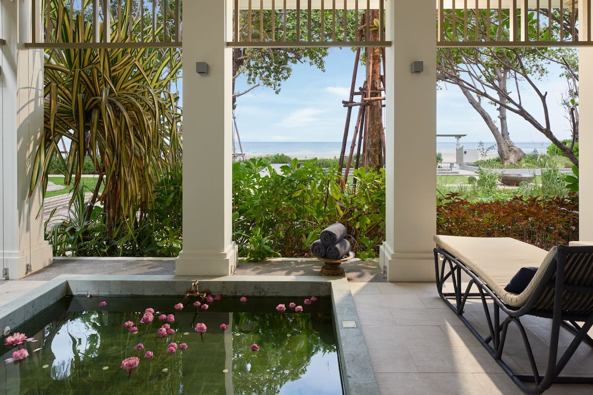 Ein Pool mit Seerosen, eine Liege und Blick auf den Strand.