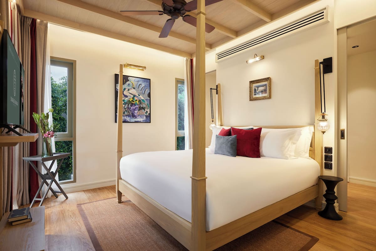 Ein Himmelsbett mit Holzrahmen, ein Deckenventilator und ein Nachttisch mit Lampe.
