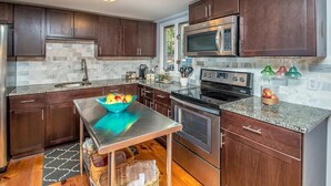 A modern kitchen with dark wooden cabinets, a stainless steel refrigerator, a microwave, an oven, and a granite countertop.
