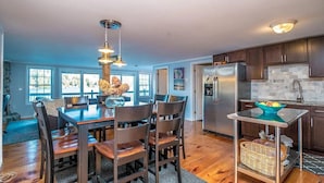 A spacious kitchen with wooden flooring, a central island, and a built-in refrigerator.