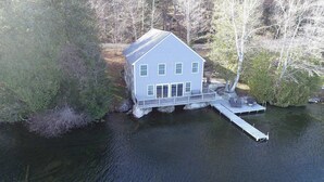 A house with a dock extending into a body of water, surrounded by trees.