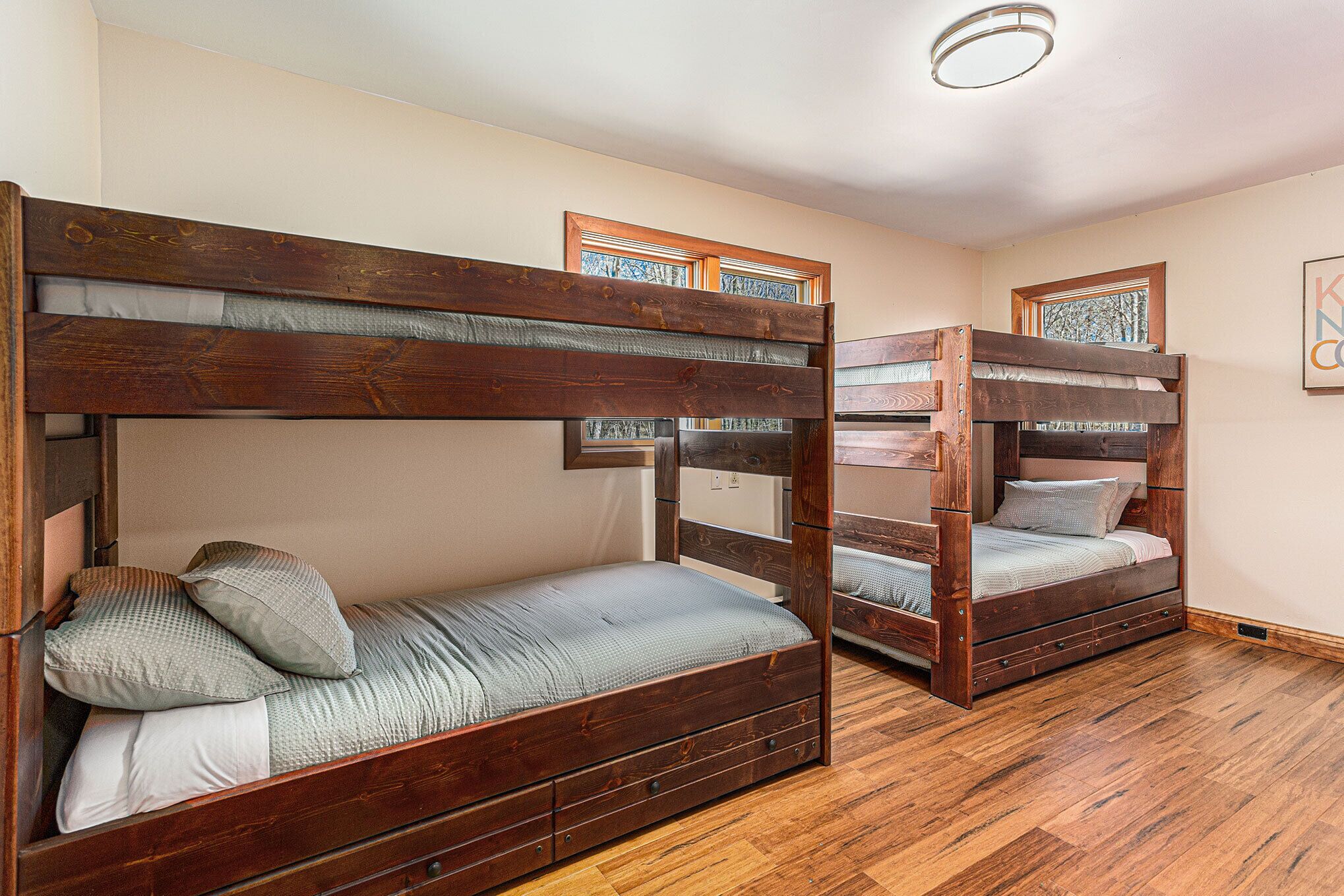 Une chambre avec deux lits superposés, un plancher en bois et des œuvres d’art encadrées accrochées aux murs.