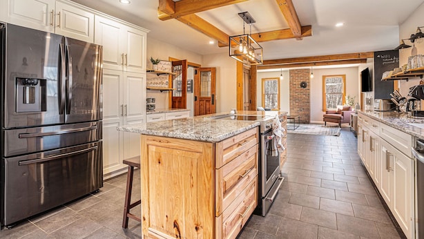 A kitchen with a large island, stainless steel appliances, wooden cabinetry, and exposed beams. - Private 40-Acre Retreat | Hot Tub, Trails, Games & Fire Pit (Hopkins)