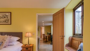 A bedroom with a bed, bedside table, lamp, and a painting on the wall. - Bradley Stables (Minehead)