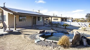 A house with a solar panel roof, a swimming pool, and a garden with a fountain. - Experience the magic of Joshua Tree. Your cozy bungalow awaits. (Twentynine Palms)
