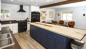 A modern kitchen with a central island, built-in appliances, and a wooden ceiling beam. - Experience the magic of Joshua Tree. Your cozy bungalow awaits. (Twentynine Palms)