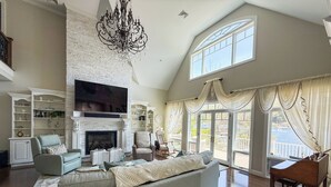 A spacious living room with a fireplace, a large television, and a piano. - Paradise Bay (Queensbury)