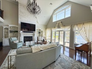 A spacious living room with a fireplace, a large television, and a piano.