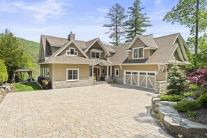 A large, two-story house with a stone foundation and a brick driveway.
