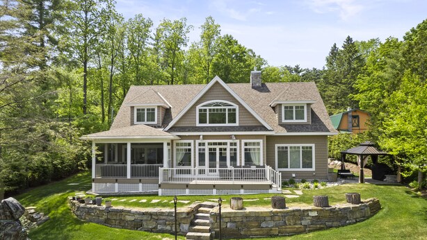 A two-story house with a covered porch, stone steps, and a stone retaining wall. - Paradise Bay (Queensbury)