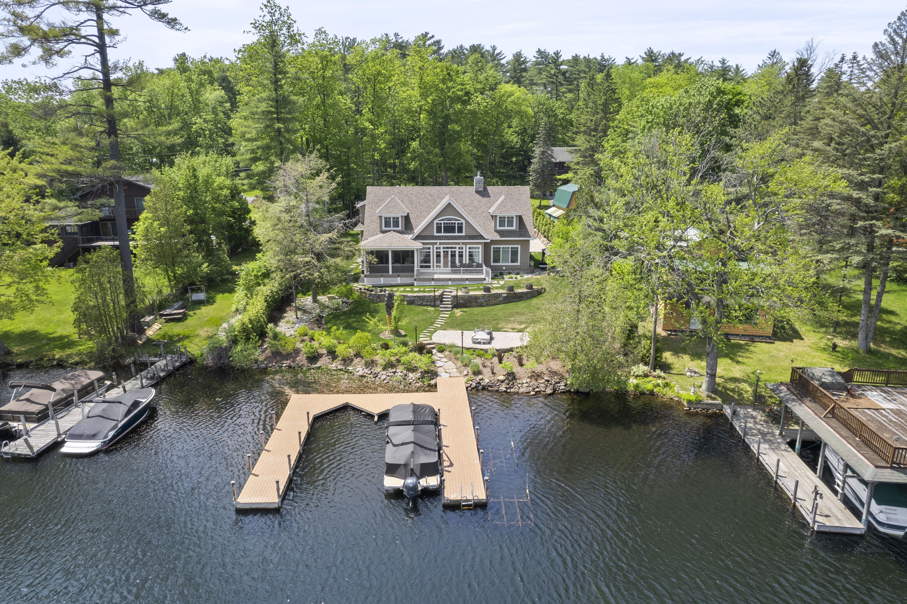 A large house with a dock and boats, surrounded by dense trees.