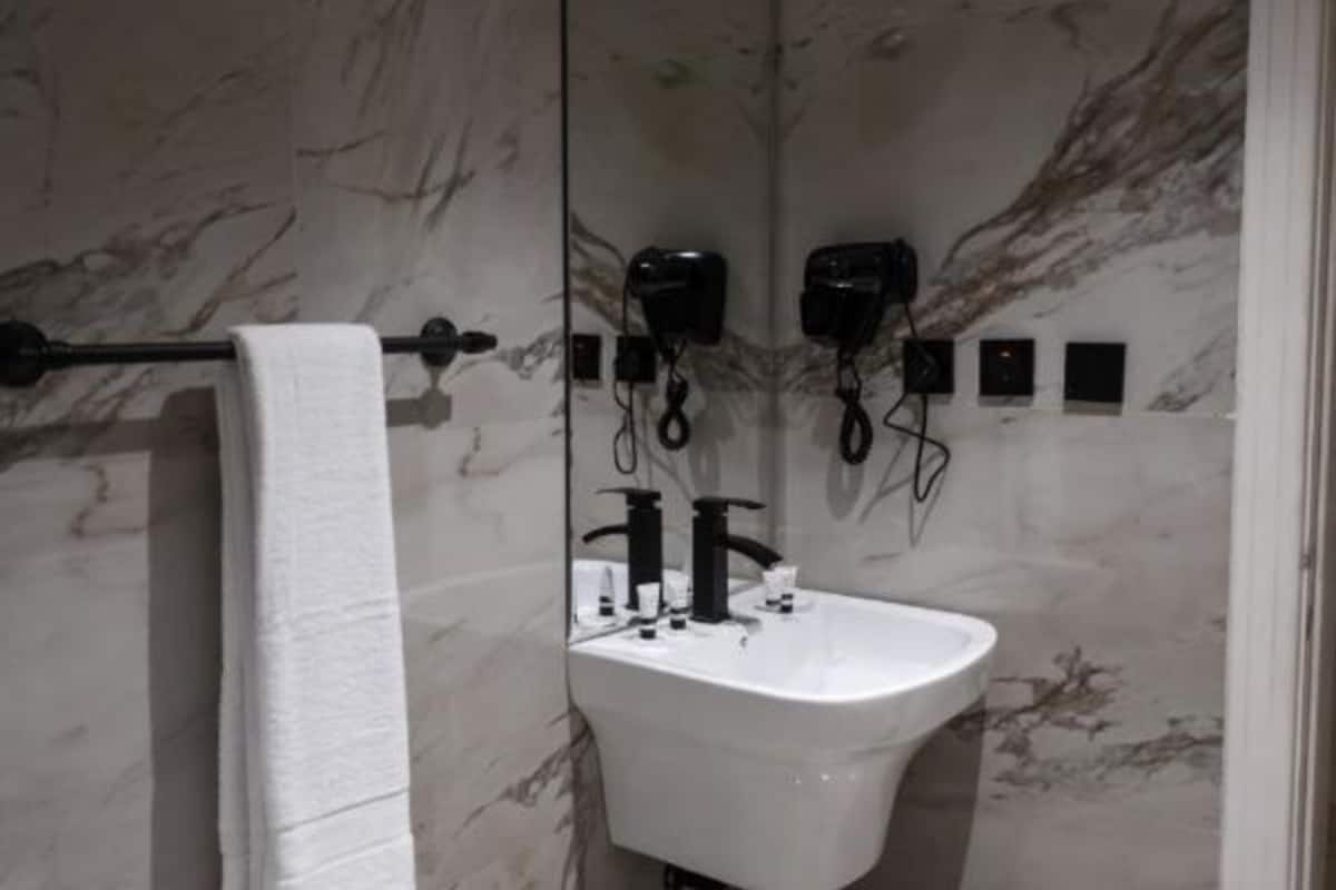 A modern bathroom with a marble wall, a white sink, and a towel rack.