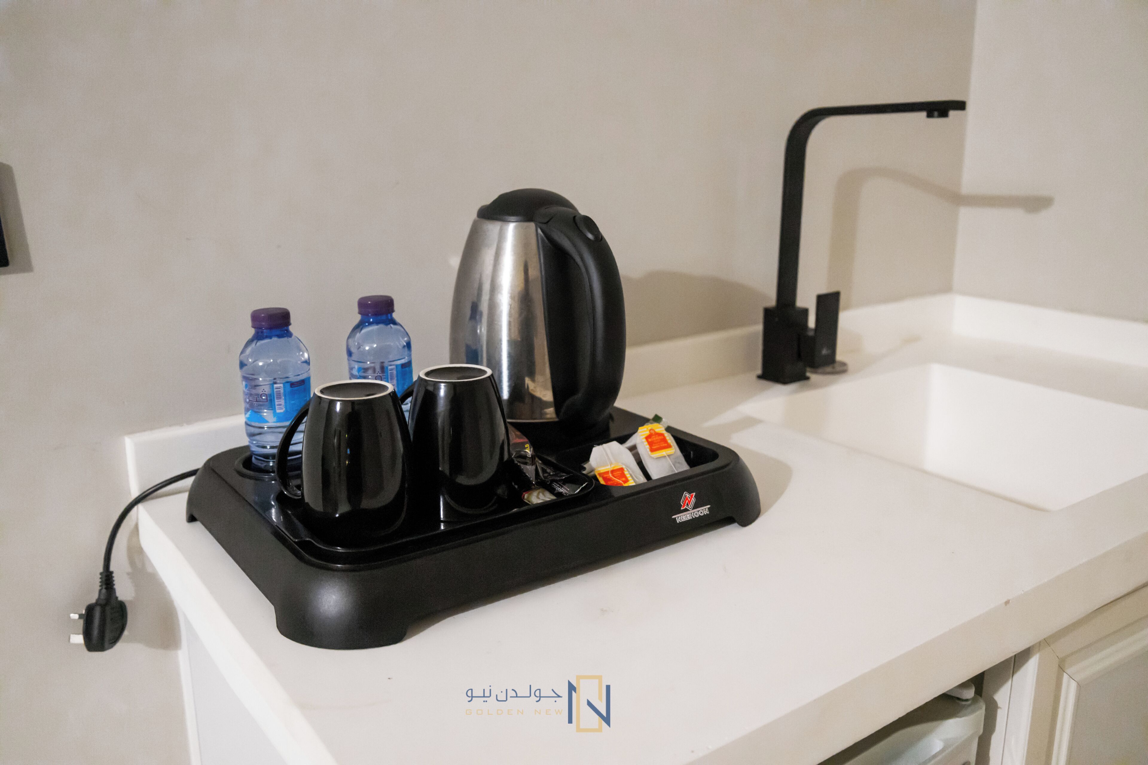 Een keukenblad met een koffiezetapparaat, twee waterflessen en een waterkoker.