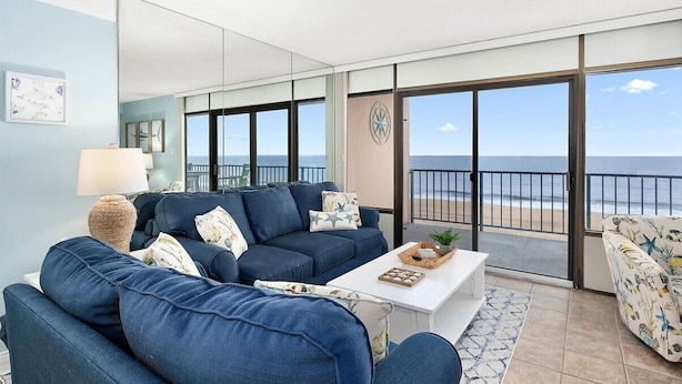 Una sala de estar con sofá, mesa de centro y vista al mar.