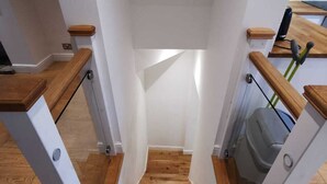 Een trap met houten leuningen en witte muren.