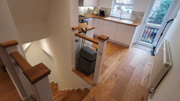 Een moderne keuken met houten vloeren, een inbouwfornuis en een raam met uitzicht op de tuin.
