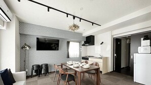 Un salon moderne comprenant un coin repas, une cuisine et un canapé blanc.