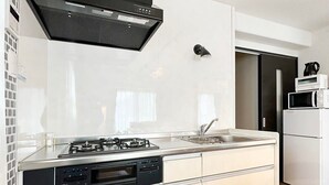 Une cuisine moderne équipée d’une cuisinière à gaz, d’un lave-vaisselle et de meubles blancs.