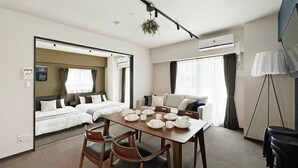 Habitación de hotel con comedor, sofá, cama y aire acondicionado instalado en el techo.