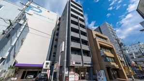 Un edificio de varios pisos con un garaje en la planta baja, un espacio comercial visible en el segundo piso y una combinación de edificios residenciales y comerciales al fondo.