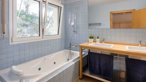 A modern bathroom with a bathtub, two sinks, a shower, and a large mirror. - Oliver House (Tarragona)