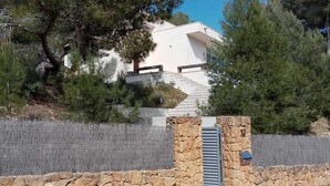 A modern house with a stone entrance, surrounded by pine trees and a stone wall. - Oliver House (Tarragona)