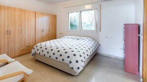 A bedroom with a bed, a chair, a wardrobe, and a window. - Oliver House (Tarragona)