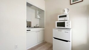 Cocina compacta con muebles blancos, microondas y refrigerador Hisense.