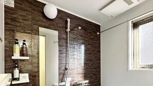 Un baño moderno con un espejo grande, paneles de madera oscura, una bañera y una ducha.