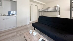 A compact living space with a kitchenette, a black sofa, and a bunk bed. - 1Br Apt with Balcony for 4 Ppl in Onomichi (Onomichi)