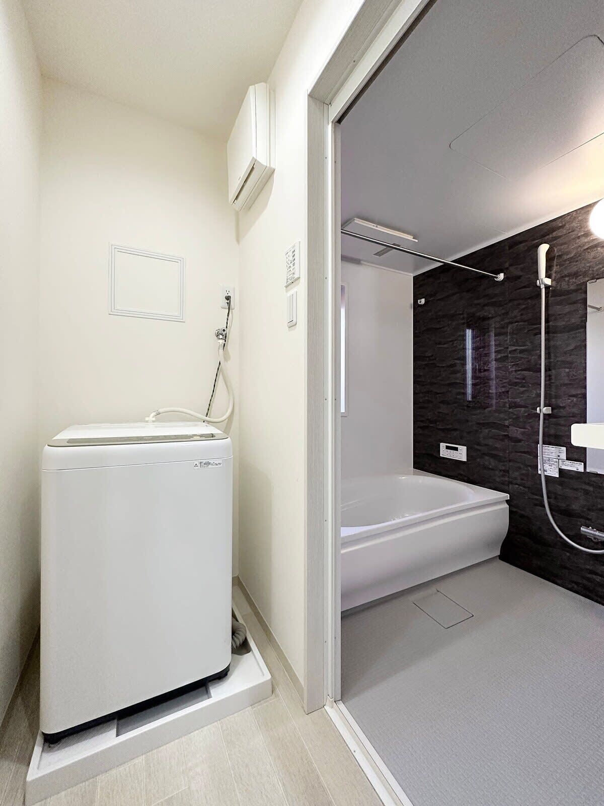 Un baño moderno con lavadora integrada, bañera y zona de ducha.
