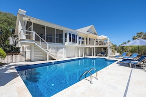 A two-story house with a swimming pool, a covered deck, and a staircase leading to the upper level.