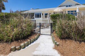 A beachfront property with a gated entrance, a covered patio, and a view of the ocean.