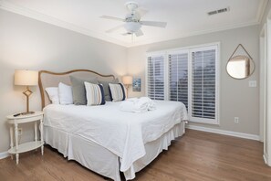 A bedroom with a bed, bedside tables, a ceiling fan, and a window with blinds.