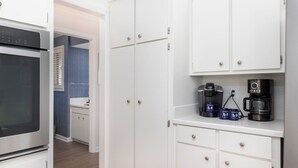 A kitchen with white cabinets, a coffee maker, and a Keurig coffee pod station. - Spacious 4-Bedroom Beach House with Pool and Ocean Views (Isle Of Palms)